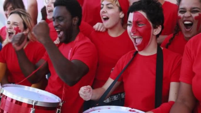 多种族红色运动球迷一边尖叫，一边支持他们的球队-足球支持者在比赛中玩耍-世界杯概念