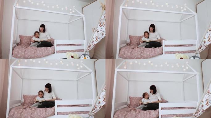 微笑的妈妈和小女儿在舒适的床上放松阅读有趣有趣的儿童书
