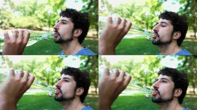 夏天在公园里，年轻人在外面喝水解渴。个人资料脸特写人喝清凉水