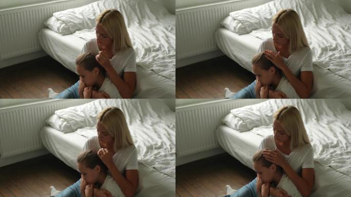 慈爱的母亲安慰得罪了不快乐的小女儿，表现出爱与关怀，表示支持，拥抱和抚摸着头发坐在地板上。