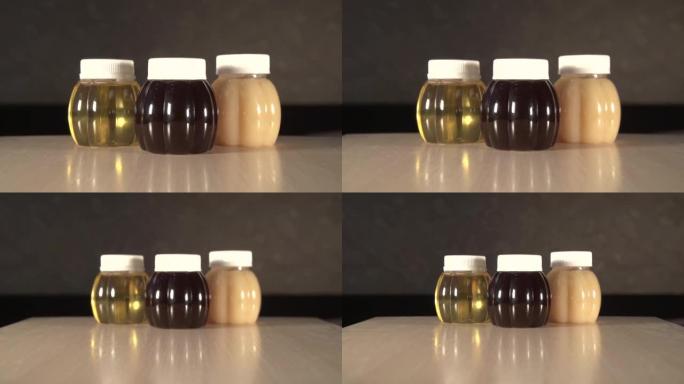 特写放大桌子上三个不同种类蜂蜜的塑料罐
