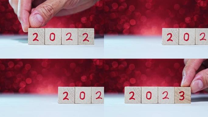 人的手换年号2022年2023年在带有红色数字的木制立方体上