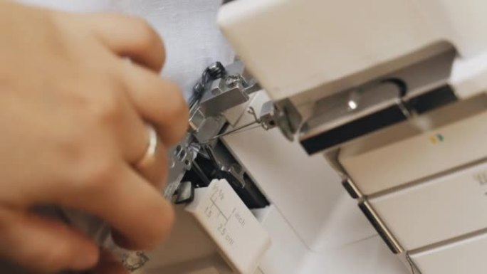 一位女设计师在包缝机上进行裁缝。