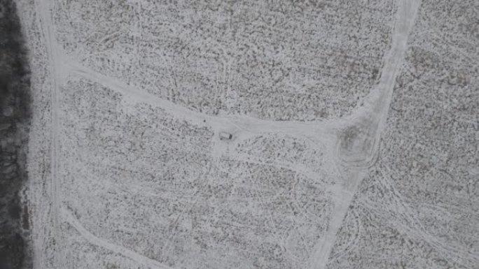 在积雪覆盖的农田上，一个人在汽车附近行走的镜头