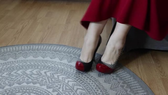成年妇女的女性腿和脚坐下来踢开红色，蓝色和白色的高跟鞋