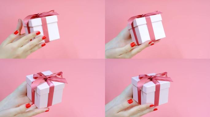 粉色背景上的女性手拿着礼品盒，侧视图。