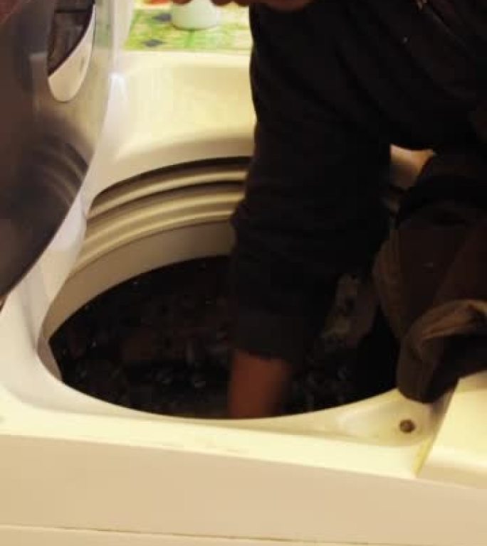 西班牙裔男子把衣服放在洗衣机里