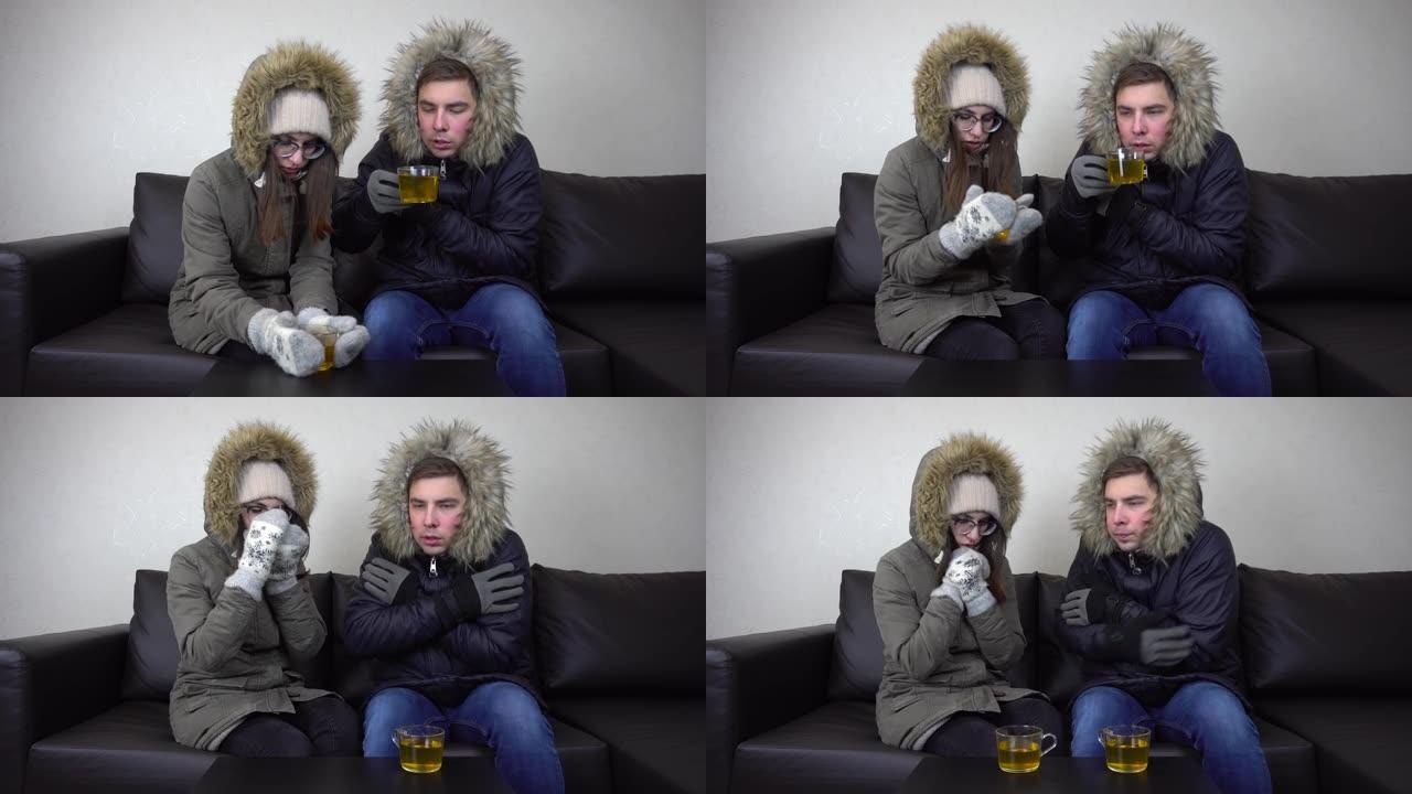 一男一女穿着夹克坐在家里喝茶。屋子里很冷，因为禁止提高屋子里的温度。一对年轻夫妇坐在没有暖气的地方。
