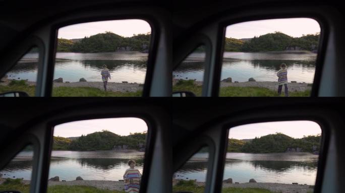 挪威湖边散步的女人。从车窗看