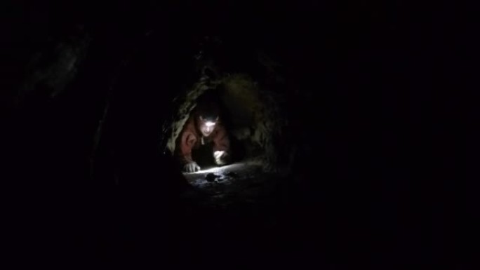 紧密黑暗洞穴通道中的女性洞穴探洞