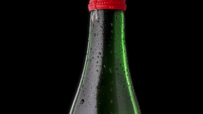 一滴从瓶子里掉下来。绿色一瓶红色瓶盖的矿泉水。水滴玻璃瓶