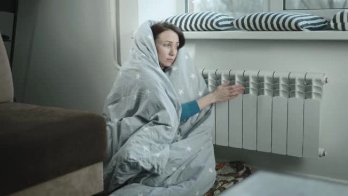 试图在散热器附近保暖的欧洲妇女。能源危机