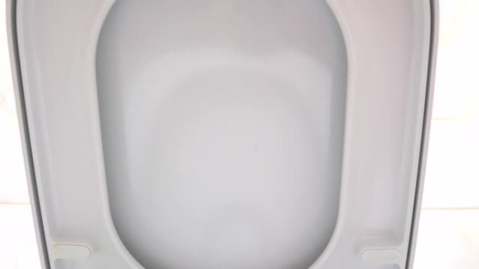 女孩用手推着浴室里白色陶瓷马桶的盖子