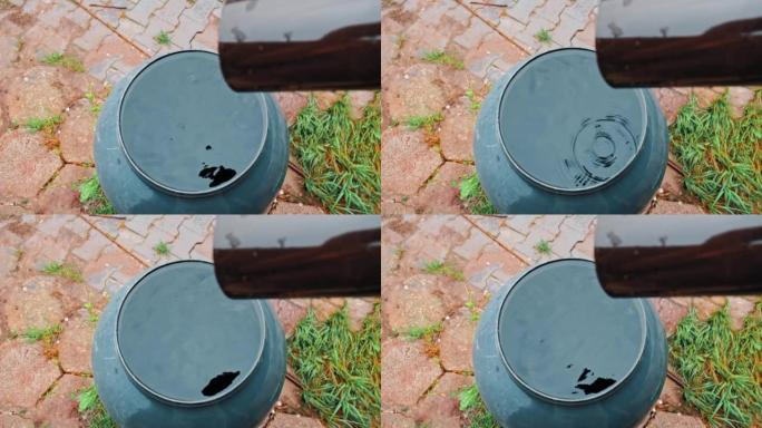 水滴从塑料排水沟滴入溢流的桶式蓄水池，用于收集雨水
