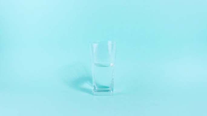 4k玻璃杯是半空或满的。玻璃透明玻璃装满了水。乐观和悲观的人生观的概念。蓝色背景。
