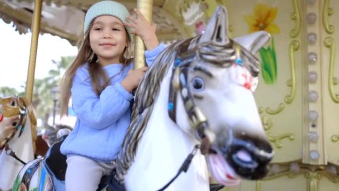 旋转木马上的漂亮孩子。可爱的女孩骑着马吸引人。有趣的庆祝活动