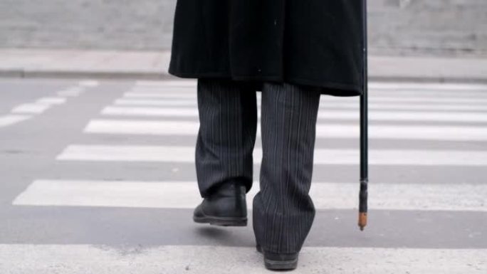 一位老退休人员穿过人行横道。一位老人在城市里走来走去