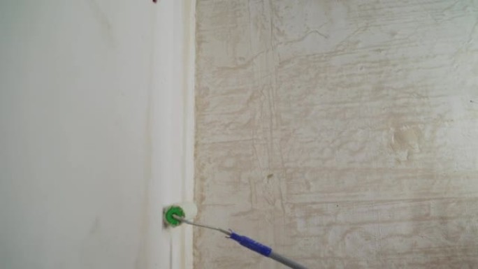 使用滚筒将底漆涂在墙壁上的过程。使用滚筒将底漆溶液涂在壁上，以去除灰尘并增加附着力。底漆处理。用滚筒