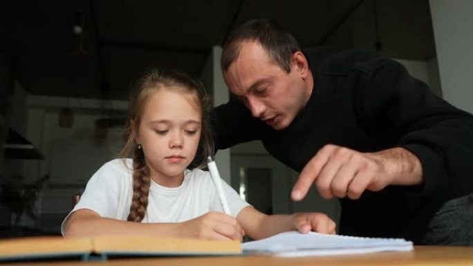 愤怒的年轻父亲大喊大叫，提高声音，责骂懒惰的小女儿坐在桌子旁做作业。父母管教孩子的概念。