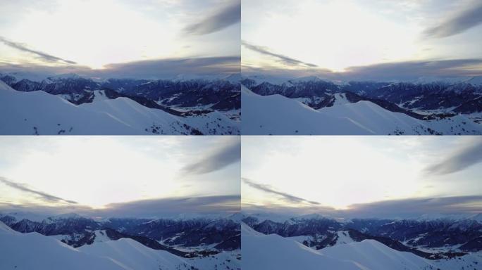 冬季日出时，雪山山坡上满是粉末的空中飞车在滑雪胜地进行自由滑行。偏远地区的山脉覆盖着初雪。高加索山峰