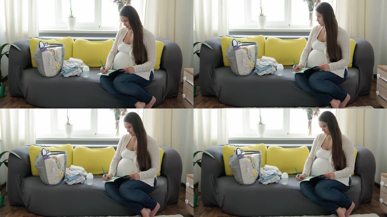 可爱的孕妇为妇产医院写装箱单笔记本准备包。怀孕的年轻莱迪在家里的黄灰色沙发上玩得开心。母亲，医学保健