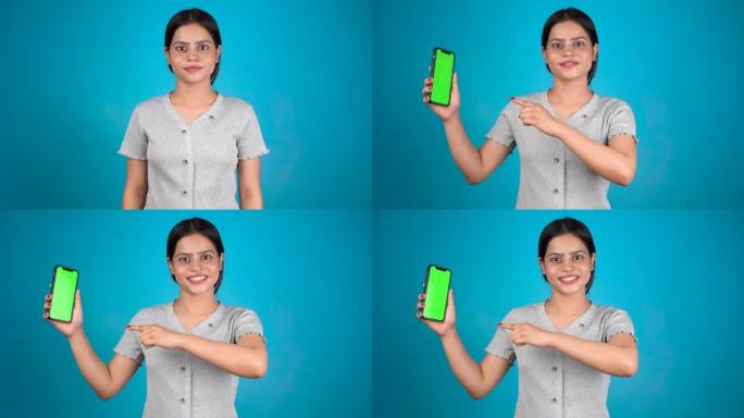 微笑的年轻女子指着智能手机屏幕，模拟手机，绿色屏幕隔离在彩色背景上的手机