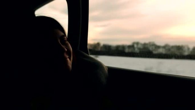 坐在汽车后座上的女人看着窗户。公路旅行概念