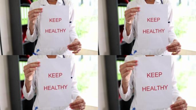 女性心脏病专家手持写有“保持健康”字样的纸