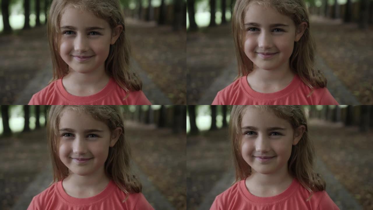 肖像微笑的小女孩看着相机。孩子在户外开心地笑。好奇的小女孩肖像。面对有趣沉思的孩子。大笑可爱的漂亮女