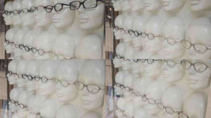 眼镜商店在白色人体模型上的展示柜在玻璃后面
