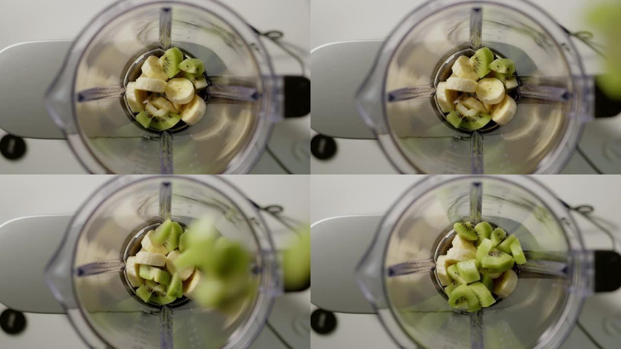 自上而下的视图猕猴桃块被扔进搅拌机做冰沙。健康生活和保持健康的素食饮料将在家里的厨房里准备。
