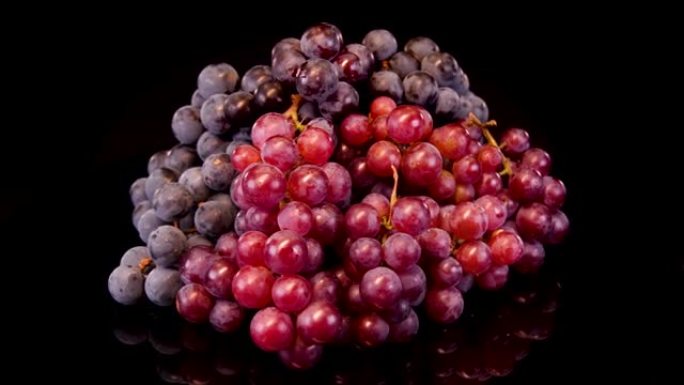 黑色背景上的葡萄。成熟的有机红葡萄堆在黑色背景上旋转。葡萄酒生产用葡萄。