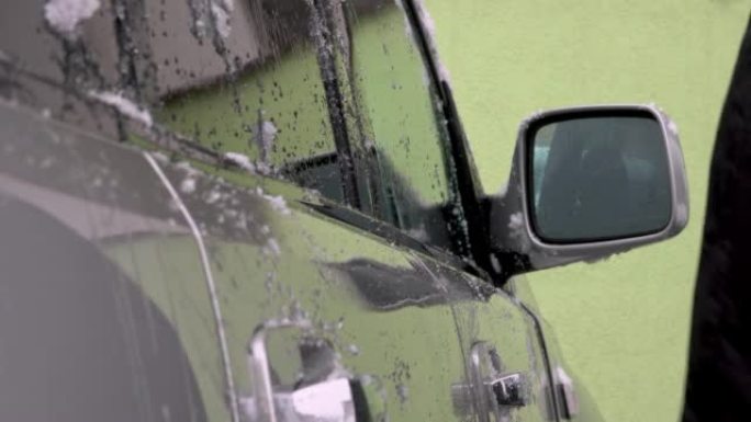 男子用冰雪清洁汽车挡风玻璃