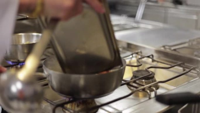 厨师手工在煎锅中烹饪食物的特写镜头在煤气炉上，专业厨师在晚餐的商业厨房中烹饪时在平底锅中搅拌肉，烹饪