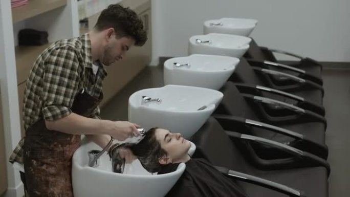 发型师在沙龙用女人的头发冲洗洗发水