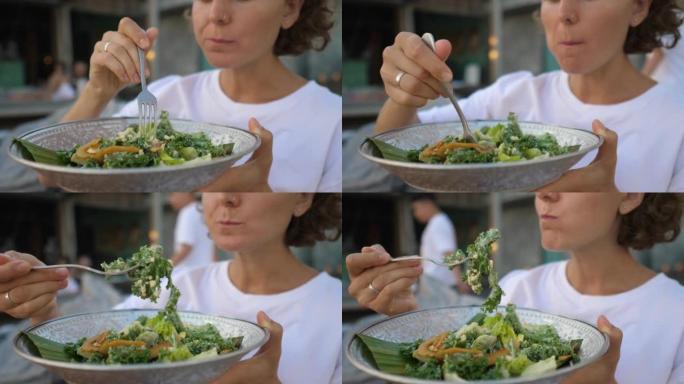 高加索女孩吃健康有机绿色素食沙拉的特写。吃高纤维含量的植物性饮食对人体有益。一个素食女人正在吃她最喜