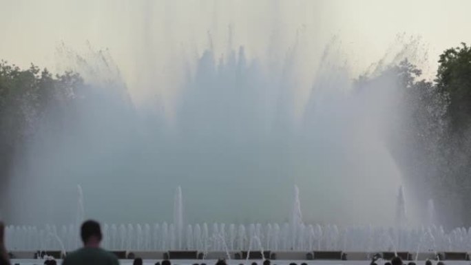 在西班牙加泰罗尼亚巴塞罗那演唱Montjuic魔术喷泉表演的日落前拍摄的一天。在人的前景剪影中。高质