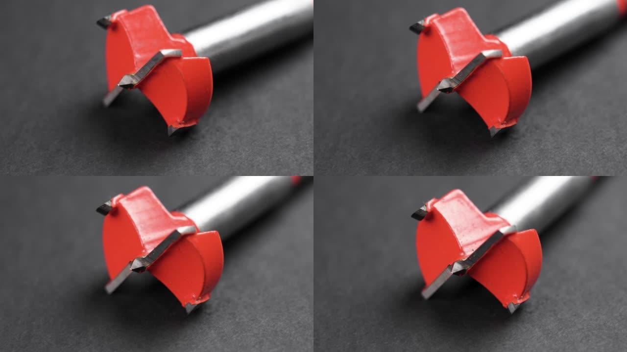 黑色背景上的Forstner钻刀，带有红色尖端，用于钻孔木材