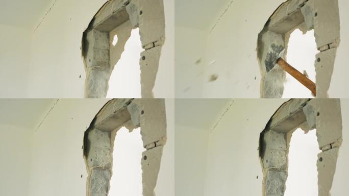 墙上一个洞的特写镜头，一个人用锤子击打它。装修期间房屋、公寓的拆除