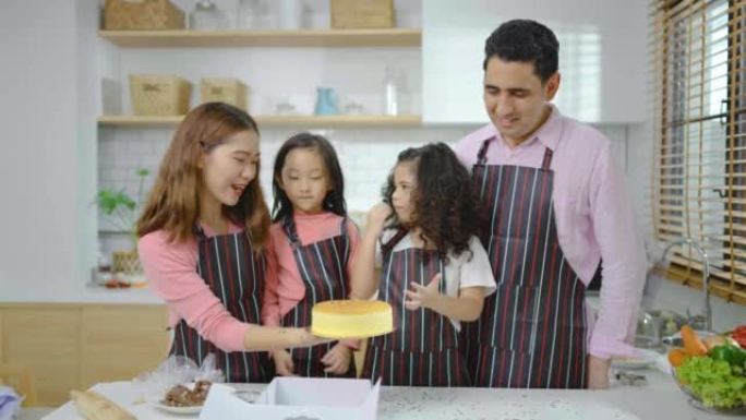 由四个不同的家庭，亚洲和阿拉伯学龄前儿童组成的小组在厨房做饭，妈妈为小女儿准备了一个蛋糕，以准备有趣