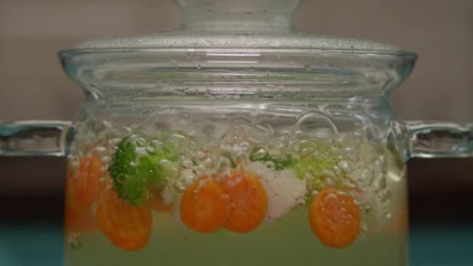 用水泡在透明锅中煮沸的蔬菜。西兰花、胡萝卜和花椰菜在慢动作中沸腾。