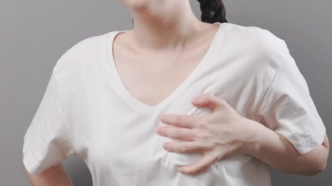 成年妇女用手抓住她的胸部，经历剧烈的疼痛。肺和心脏病。特写。心脏病发作和梗塞的概念