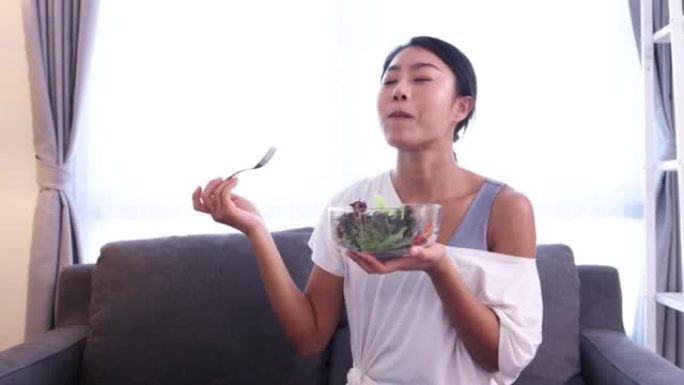 亚洲女子穿瑜伽服在家吃新鲜沙拉素食概念