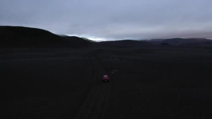 冰岛沿着火山土壤山谷行驶的汽车的鸟瞰图。