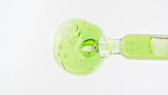 带有透明绿色化妆品凝胶液的移液器，带有白色背景上的分子气泡油的血清。天然有机化妆品、药物的宏观拍摄。