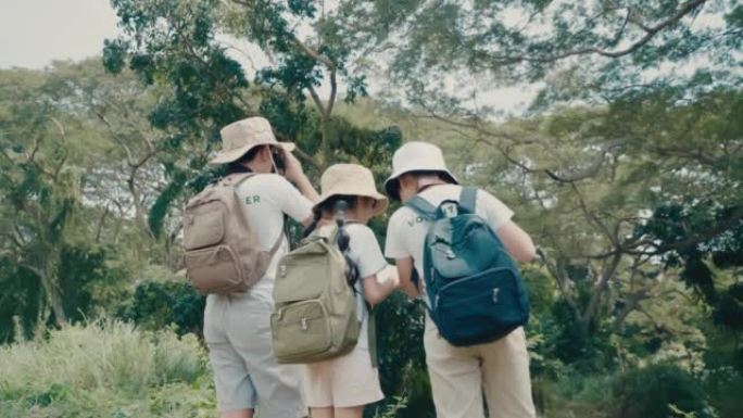 冒险和探索一个6-12岁的亚洲儿童男孩和女孩，他们有自然之旅实地考察休闲活动，在热带森林里用双筒望远