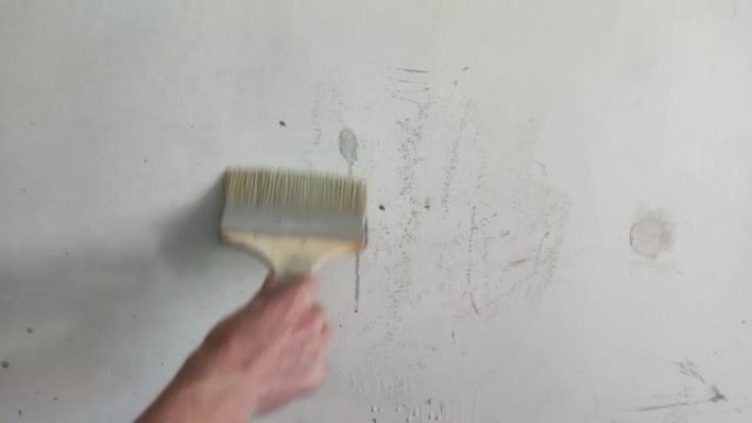 用刷子注满墙壁。男人用手给墙打底。准备粉刷墙。