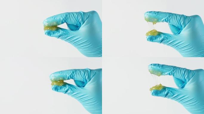 工人用两根手指挤压锂润滑脂，并在实验室中看到隔离在白色背景上的润滑脂纤维。手指上的黄色透明油脂。测试