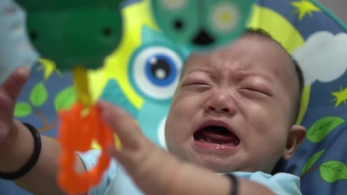 婴儿在玩拨浪鼓音乐婴儿玩具时哭泣