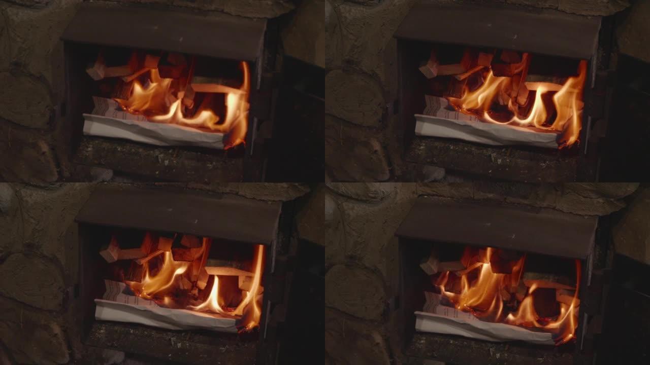 木柴旁边的炉子里正在燃烧一张皱巴巴的纸。木柴从燃烧的叶子上点燃，提供温暖。炉火的概念。